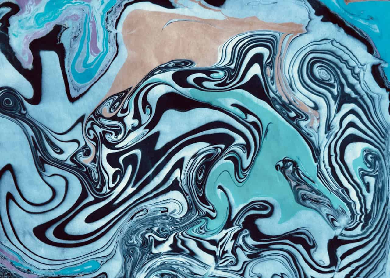 A suminagashi marbled paper print featuring bold wave-like patterns in teal, black, and white ink, created by floating ink on water in a traditional Japanese marbling class