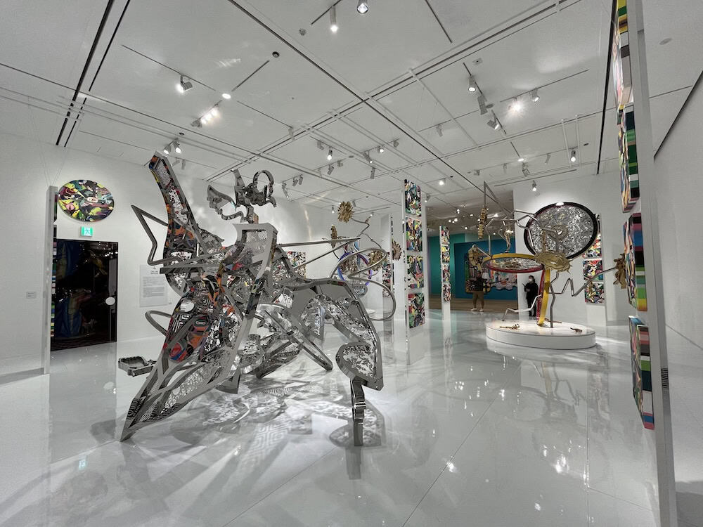 Abstract three-dimensional metal sculpture installation with intricate interconnected geometric forms and mixed media elements in minimalist white gallery space, showcasing contemporary Japanese sculptural art