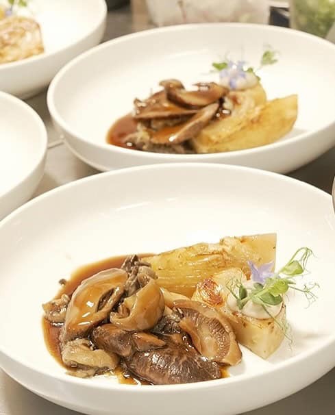 Elegant plated main course dish featuring premium Sugimoto shiitake mushrooms with sautéed mushrooms, tender protein, and seasonal vegetables on white ceramic plate at Third Kingdom restaurant