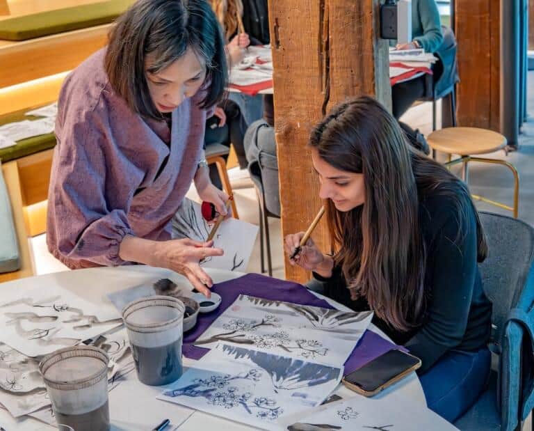Instructor guiding a student through a sumi-e brushstroke