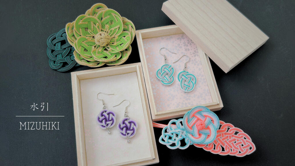 Handcrafted mizuhiki accessories and decorative knot ornaments presented in wooden boxes