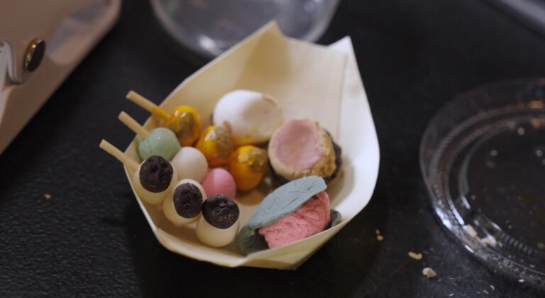 Handcrafted miniature Japanese sweets — dango, wagashi, and seasonal confections — arranged in a tiny wooden boat dish