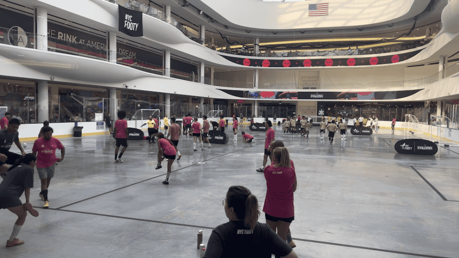 NYC Footy Cup of Dreams indoor 5v5 soccer tournament at American Dream mall, with amateur soccer players in maroon and black team jerseys competing on professional ice rink converted to soccer field, featuring multiple teams and