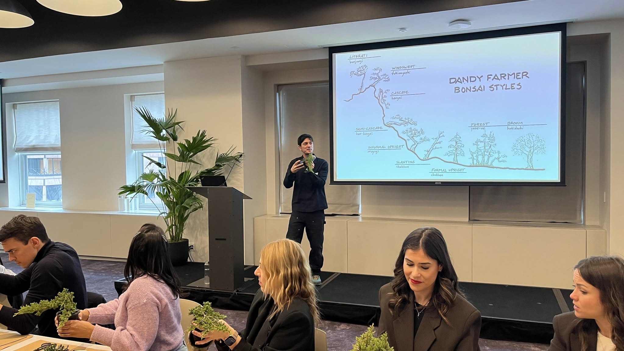 Bonsai instructor presenting bonsai styles to participants at a corporate workshop in New York