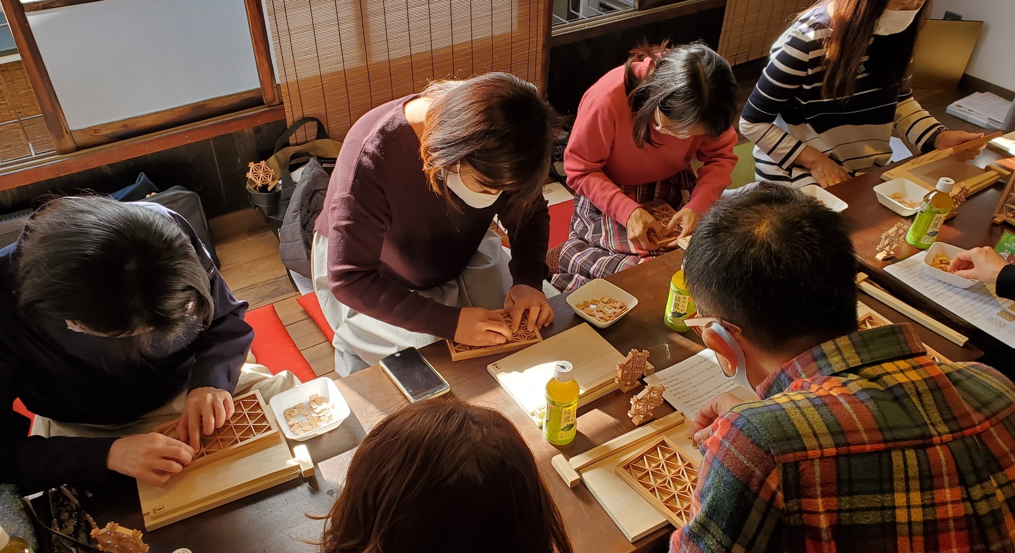 Students assembling kumiko wood lattice panels around a table during a workshop