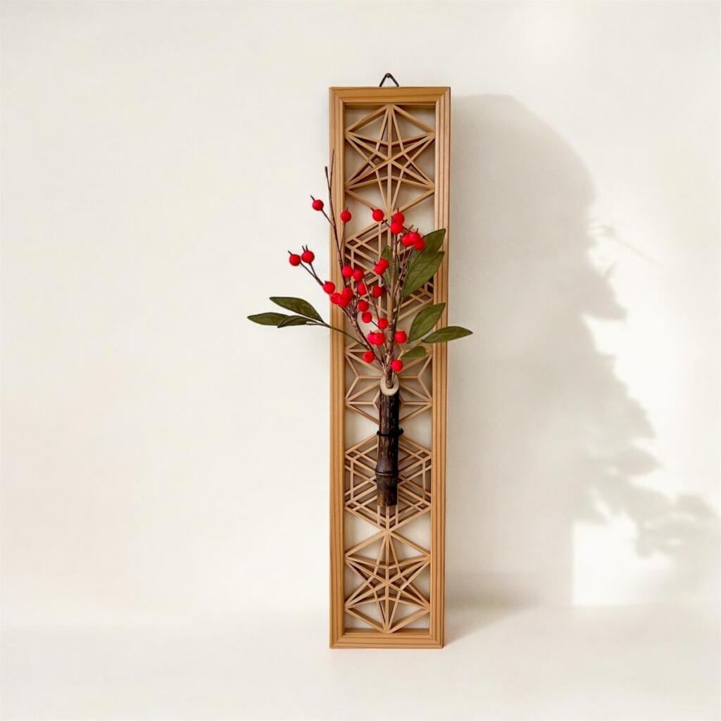 Wall-hung kumiko lattice panel with a bamboo bud vase holding red berries