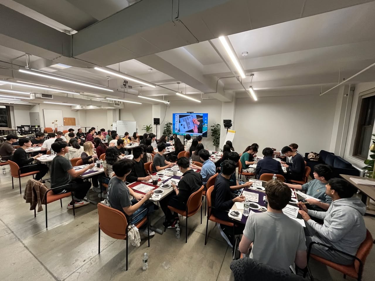 Around sixty participants painting sumi-e at a corporate workshop in a Manhattan office