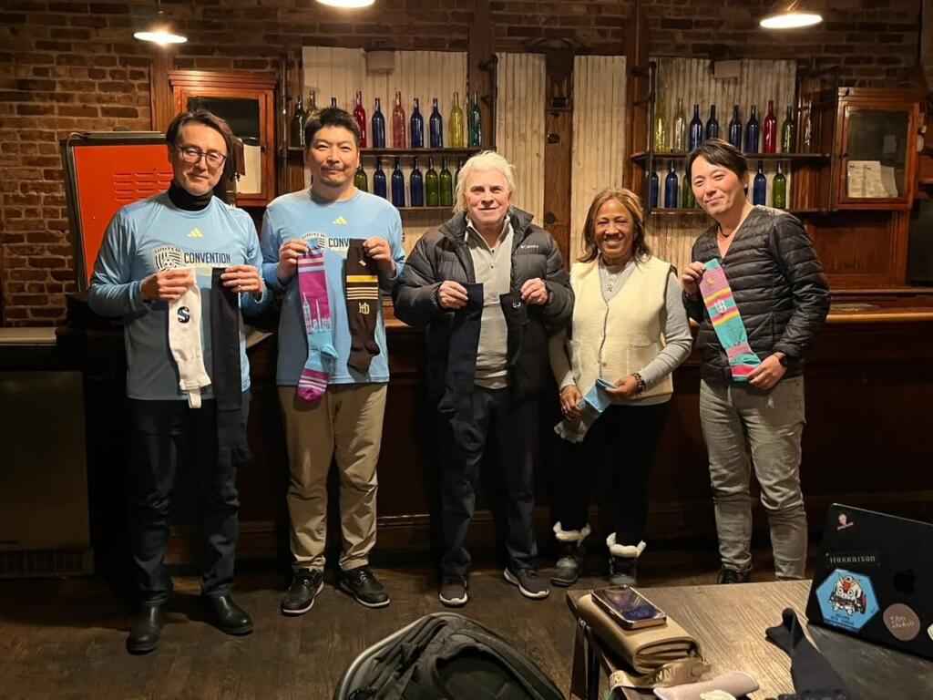 The Ueda and New York Magic teams holding Ueda sports socks after a business meeting in New York