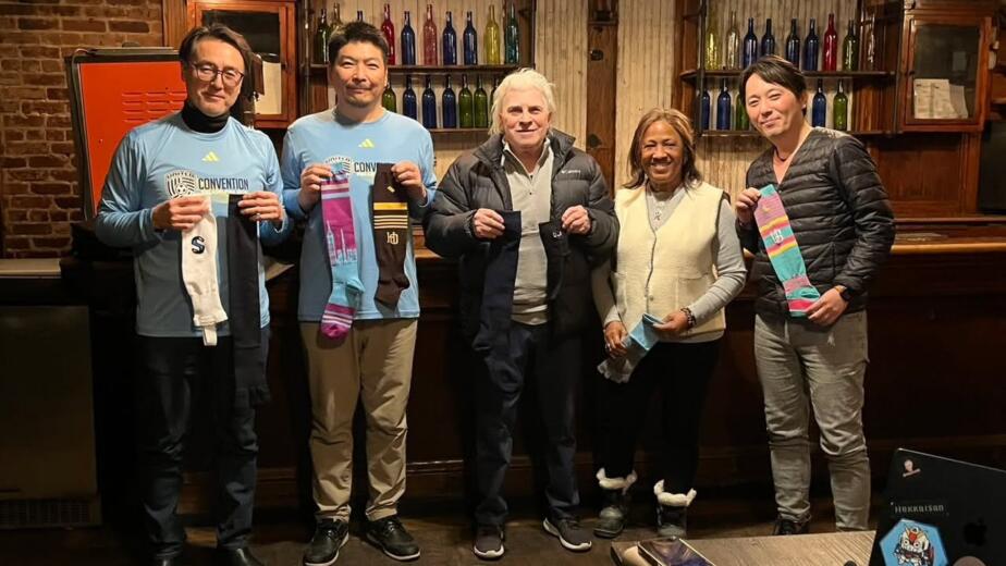 The Ueda and New York Magic teams holding Ueda sports socks after a business meeting in New York