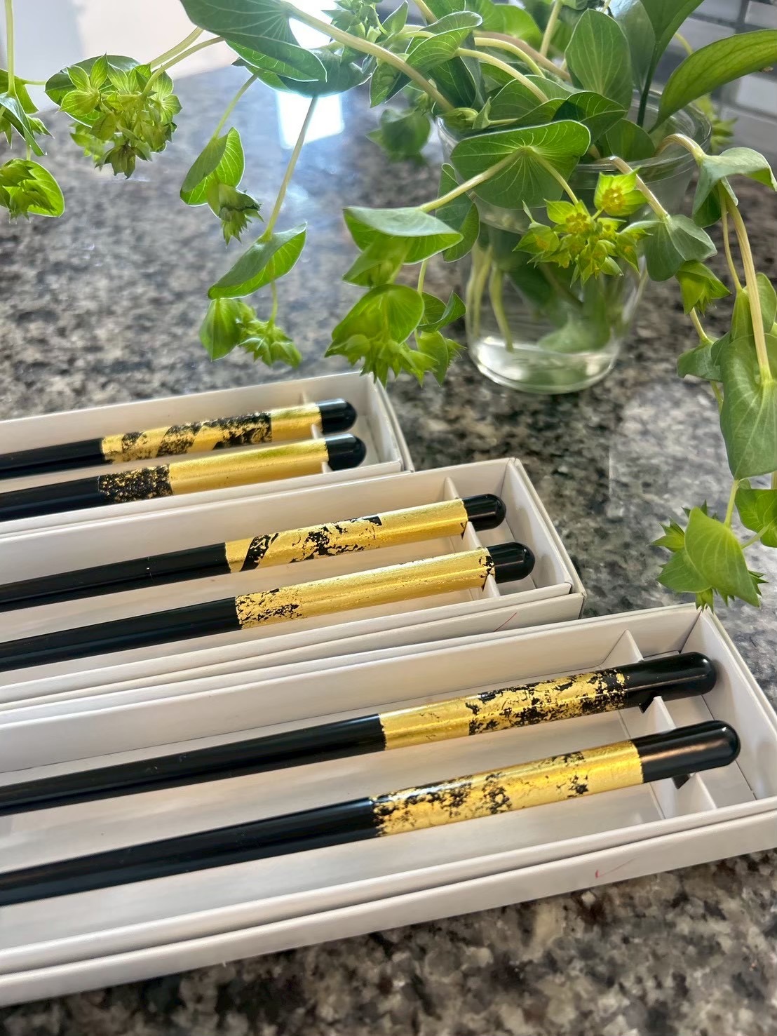 Three boxed pairs of chopsticks decorated with gold leaf, each with a different design