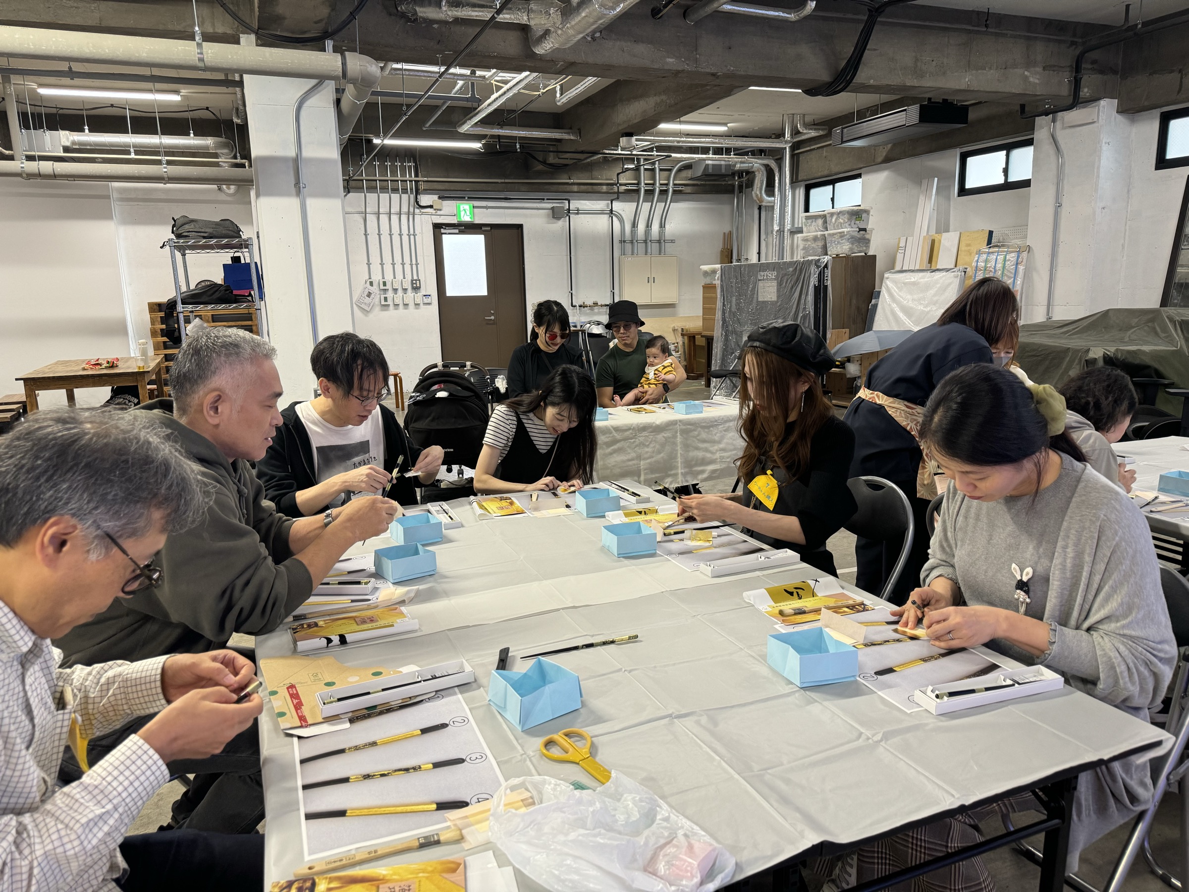 Participants applying gold leaf to their own chopsticks at a gold leaf workshop