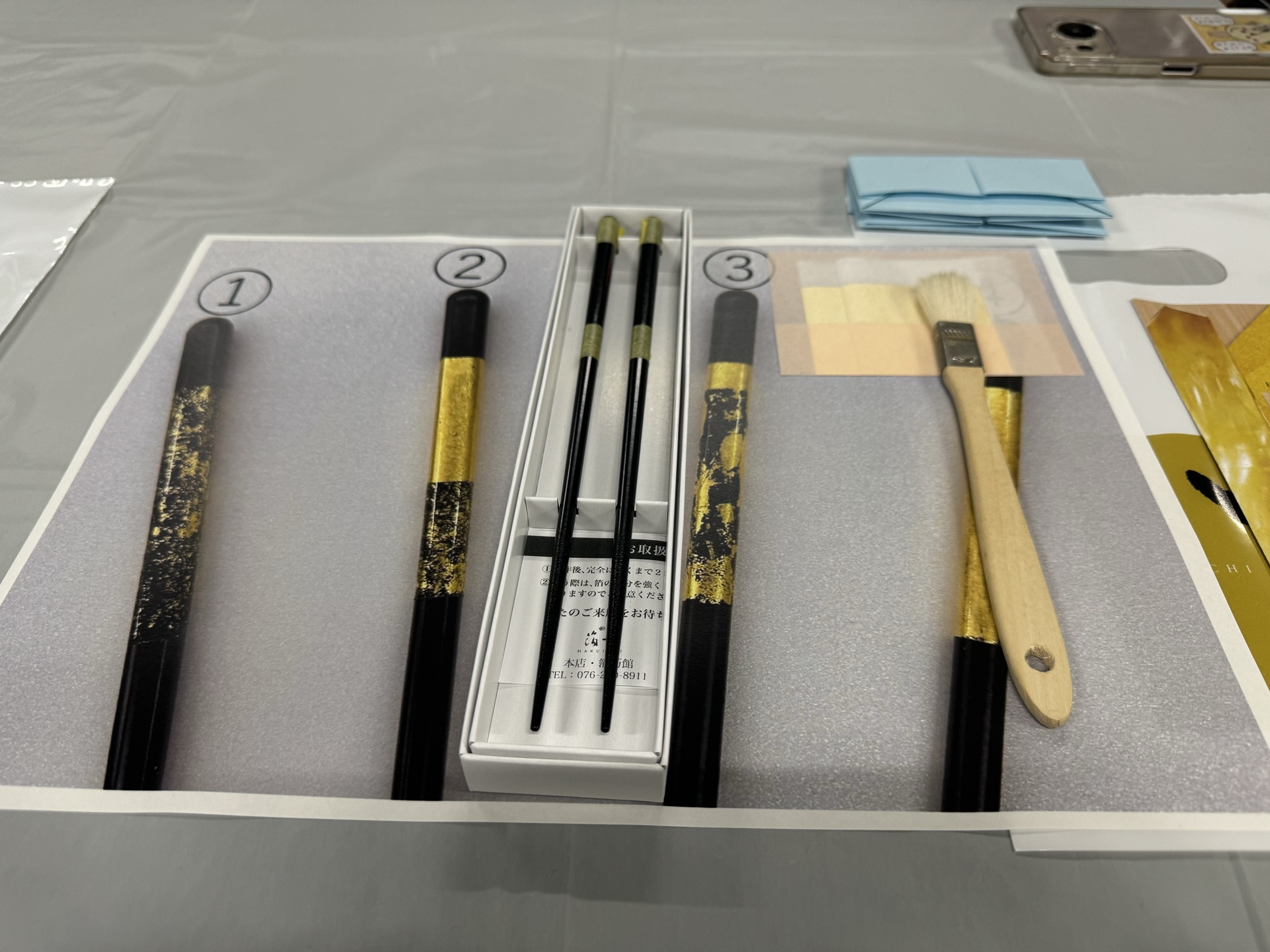 The gold leaf kit laid out on the table: three sample designs, a boxed pair, a brush and sheets of gold leaf