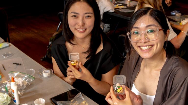 Two participants holding up the miniature bento boxes they made in the workshop