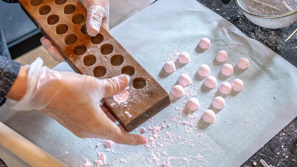 Pink wasanbon rounds turned out of a wooden mold onto parchment paper