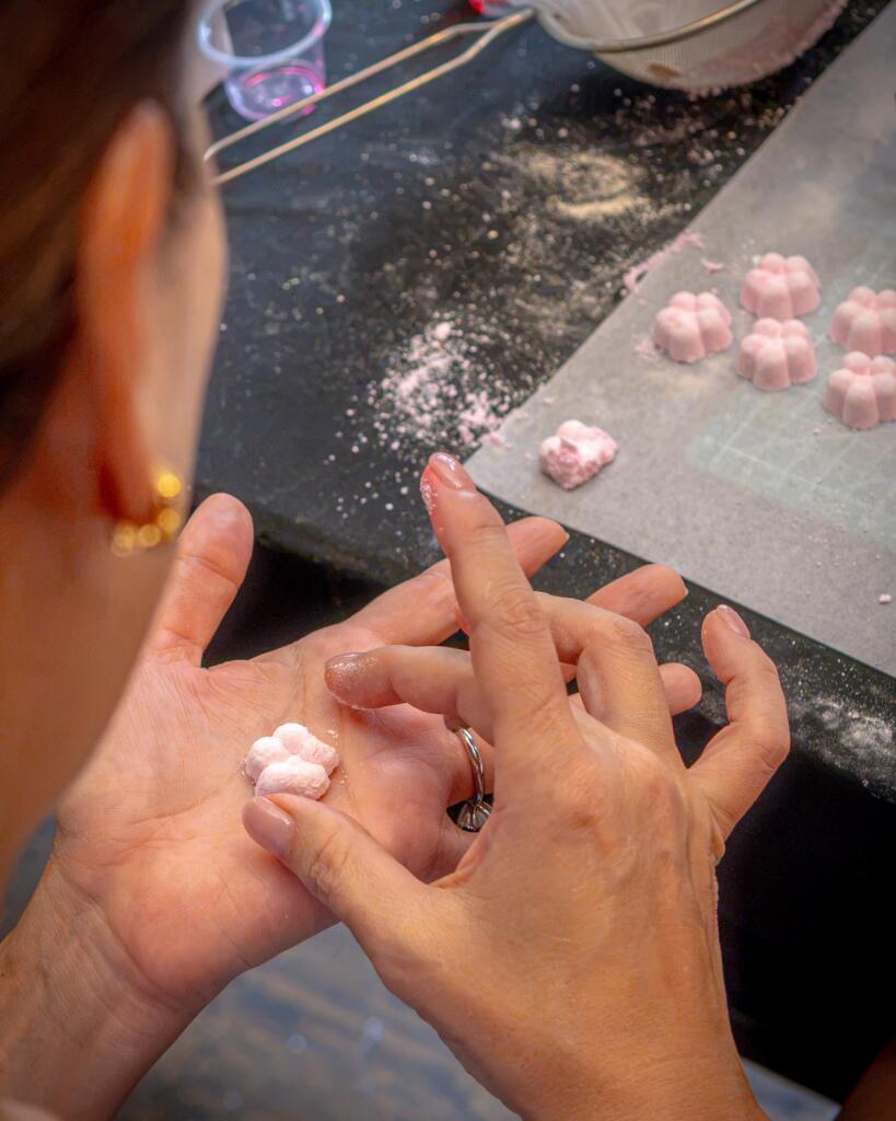 A student shaping a small pink wasanbon flower in the palm of the hand