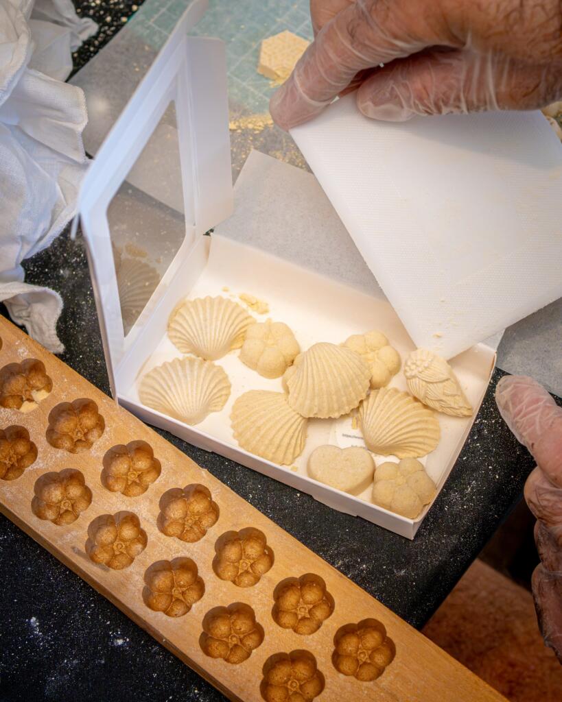 Finished wasanbon sweets in shell and chrysanthemum shapes beside a carved wooden mold