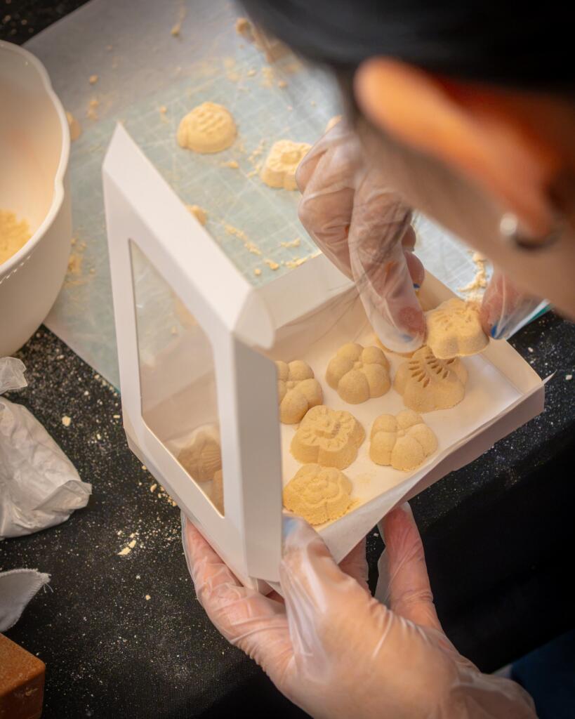A student placing finished wasanbon sweets into a windowed takeaway box