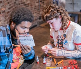 Two participants assembling a Gundam model kit together at a RESOBOX build night