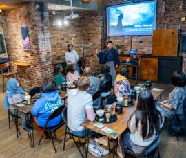 Tea master Yoshitsugu Nagano in hakama presenting to a full class during a chanoyu Japanese tea ceremony session at RESOBOX, with matcha tools set at each seat