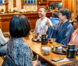 A lively group of participants sharing laughs with a kimono-clad instructor during a chanoyu Japanese tea ceremony class at RESOBOX