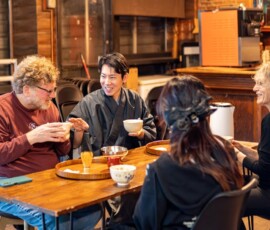 A tea ceremony instructor in kimono sharing matcha with participants around a wooden table during a chanoyu Japanese tea ceremony class at RESOBOX