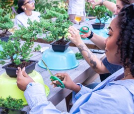 Participants trimming juniper bonsai trees with scissors during an outdoor rooftop bonsai class in New York City