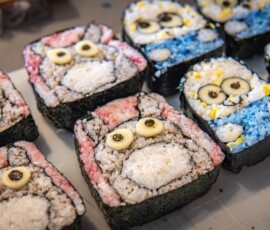 Handmade kazari maki zushi sushi rolls shaped into cartoon character faces with pink and blue colored rice, made at a decorative sushi workshop