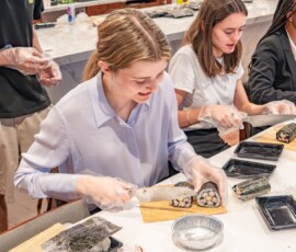 Participants slicing their handmade decorative sushi rolls during a kazari maki zushi workshop, revealing colorful cross-section designs