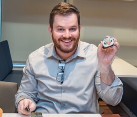 A smiling workshop participant proudly holding up a handmade kazari maki zushi roll shaped like a bird face